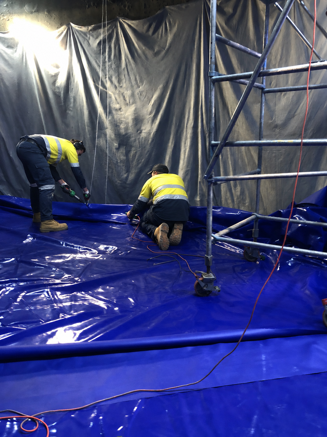 Workers installing RPVC liner inside a large concrete reservoir