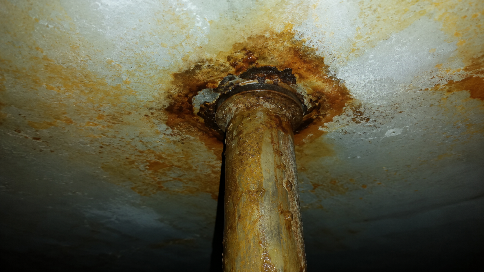 Corroding internal tank fitting with orange-brown staining inside a potable water tank